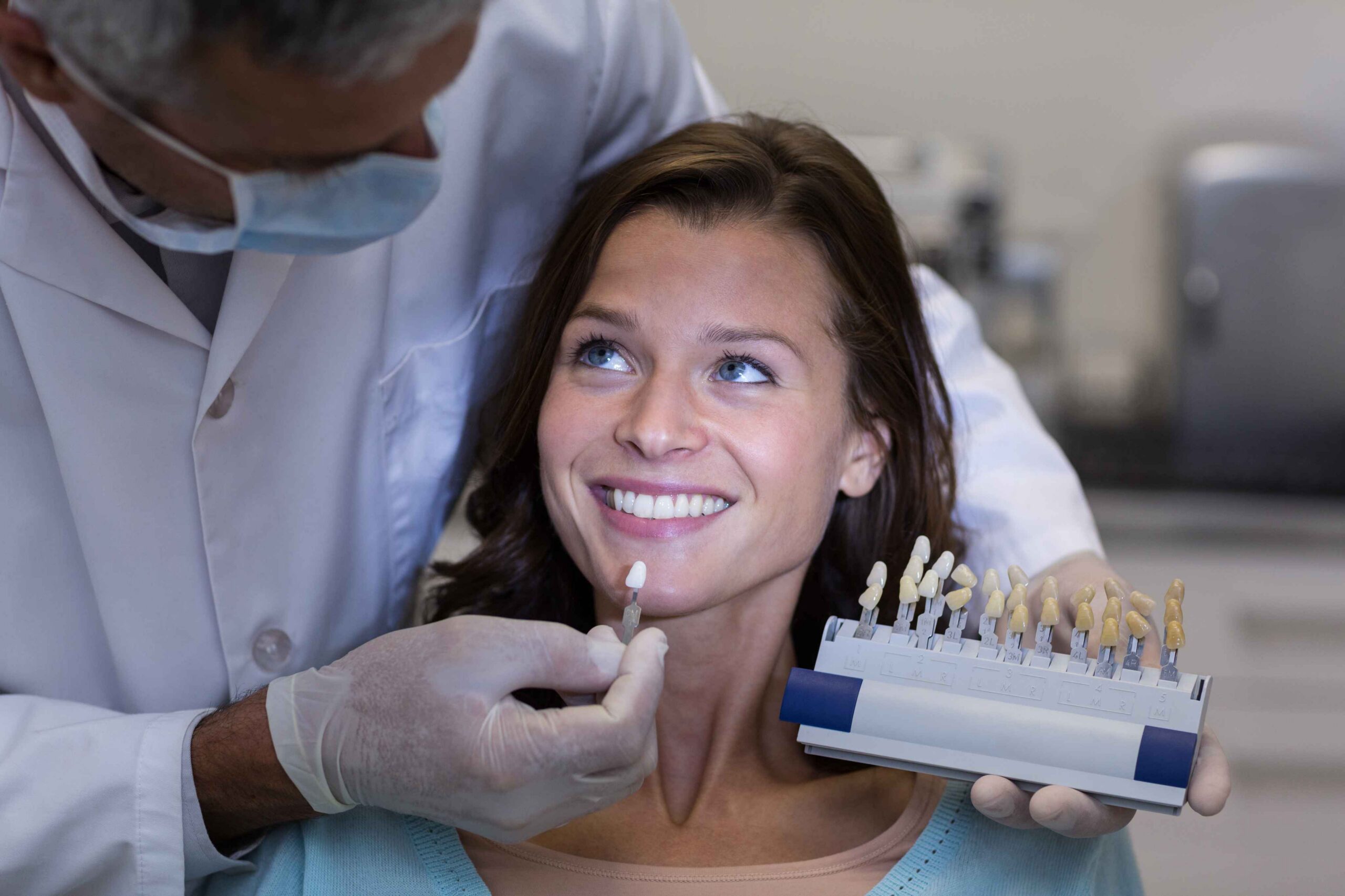 Dentist comparing tooth shade with patient during consultation